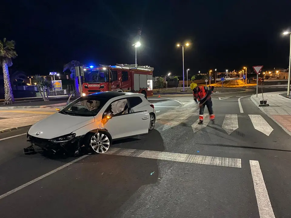 El coche siniestrado y los bomberos limpiando la calzada