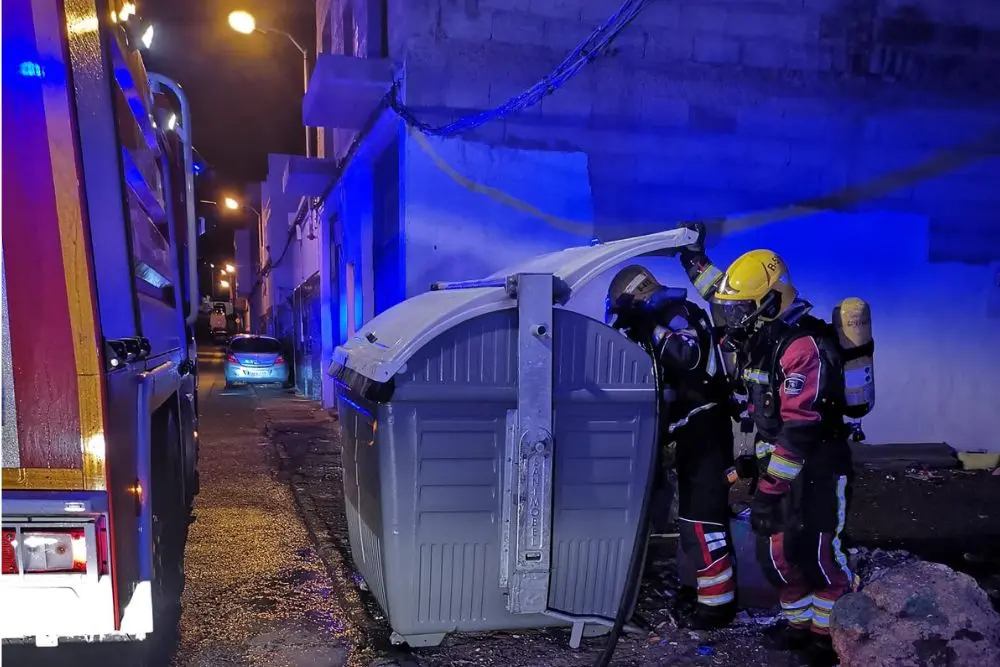 Los bomberos apagando uno de los contenedores