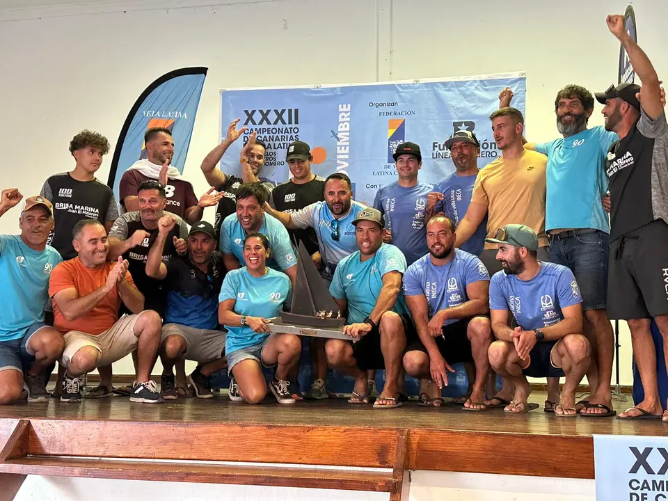 Foto de familia de los equipos del municipio de Yaiza con Virgina Morales, en primer plano, sosteniendo el trofeo de campeones.