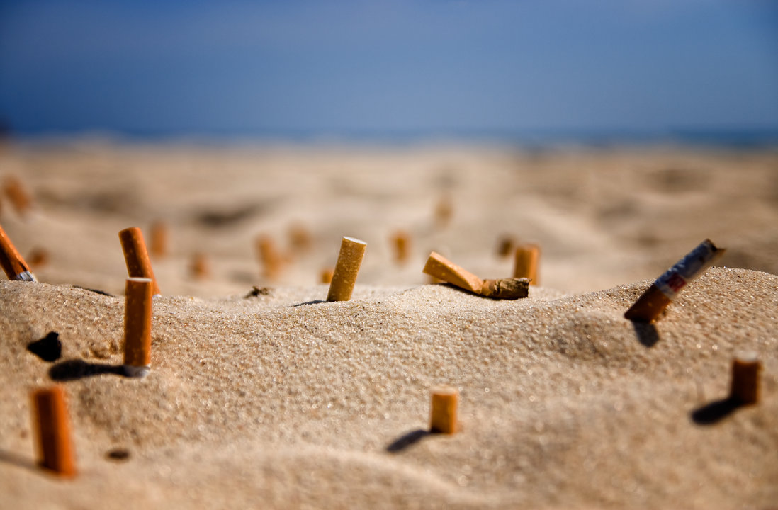 Colillas de cigarrillos en la arena de una playa.