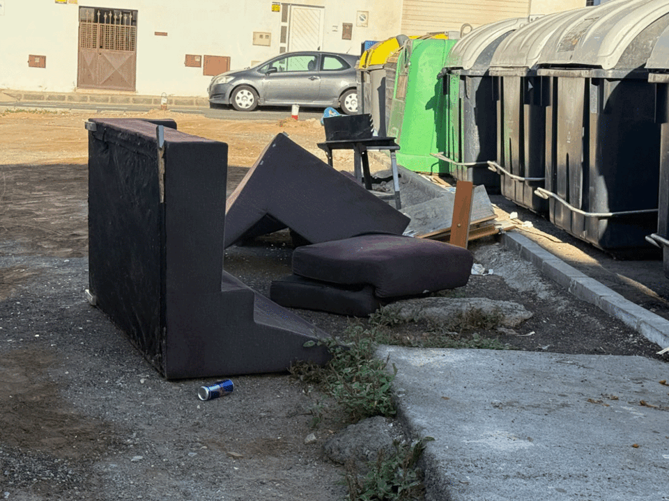 Sillones abandonados junto a contenedores