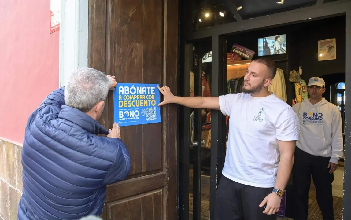 El vicepresidente del Gobierno cuelga un cartel en un establecimiento adherido.jpg