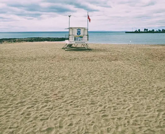 Izada la bandera roja en la Playa de El Reducto, Al fondo a la derecha la Punta del Camello donde el Consorcio del Agua y Canal Gestión tienen en aliviadero del emisario, originario de la contaminación