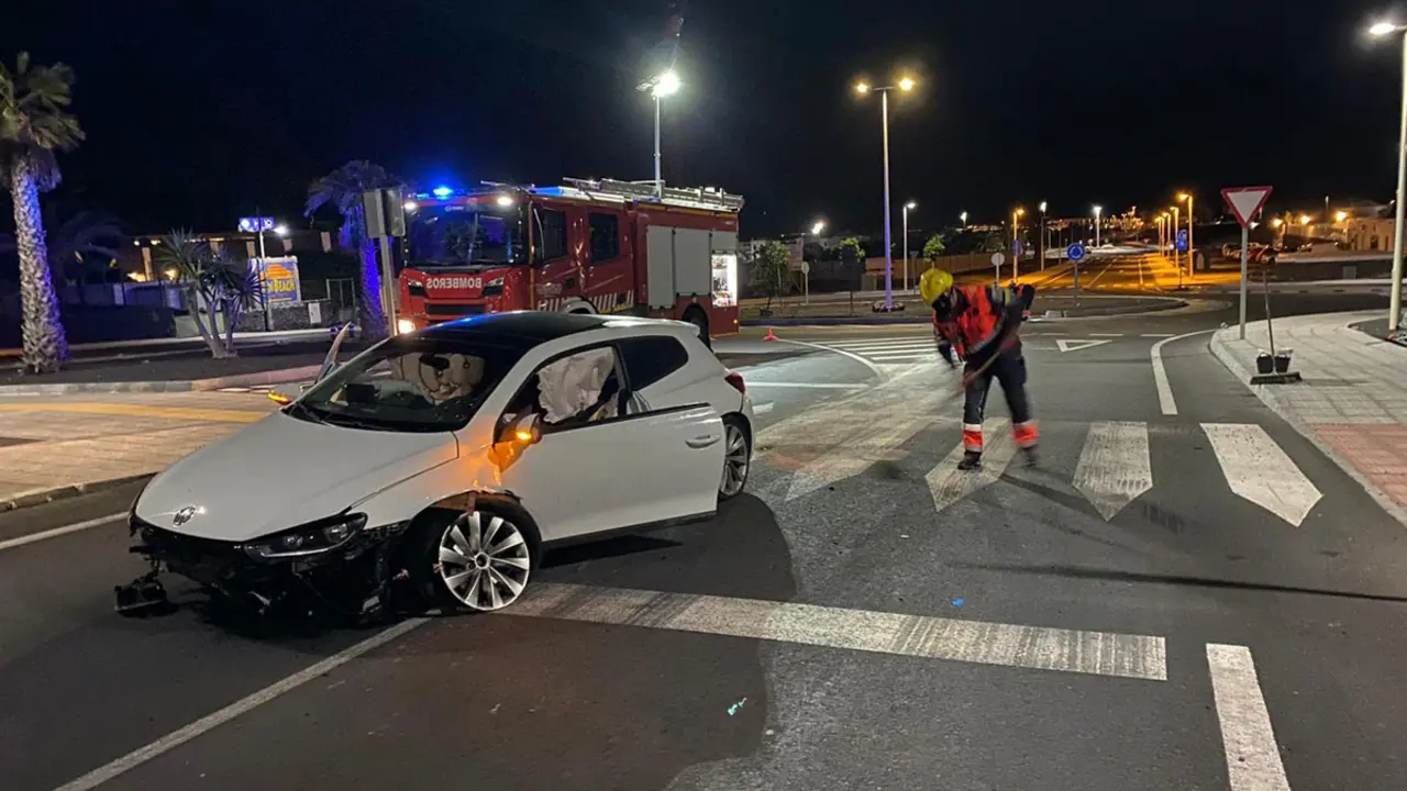 El coche siniestrado y los bomberos limpiando la calzada