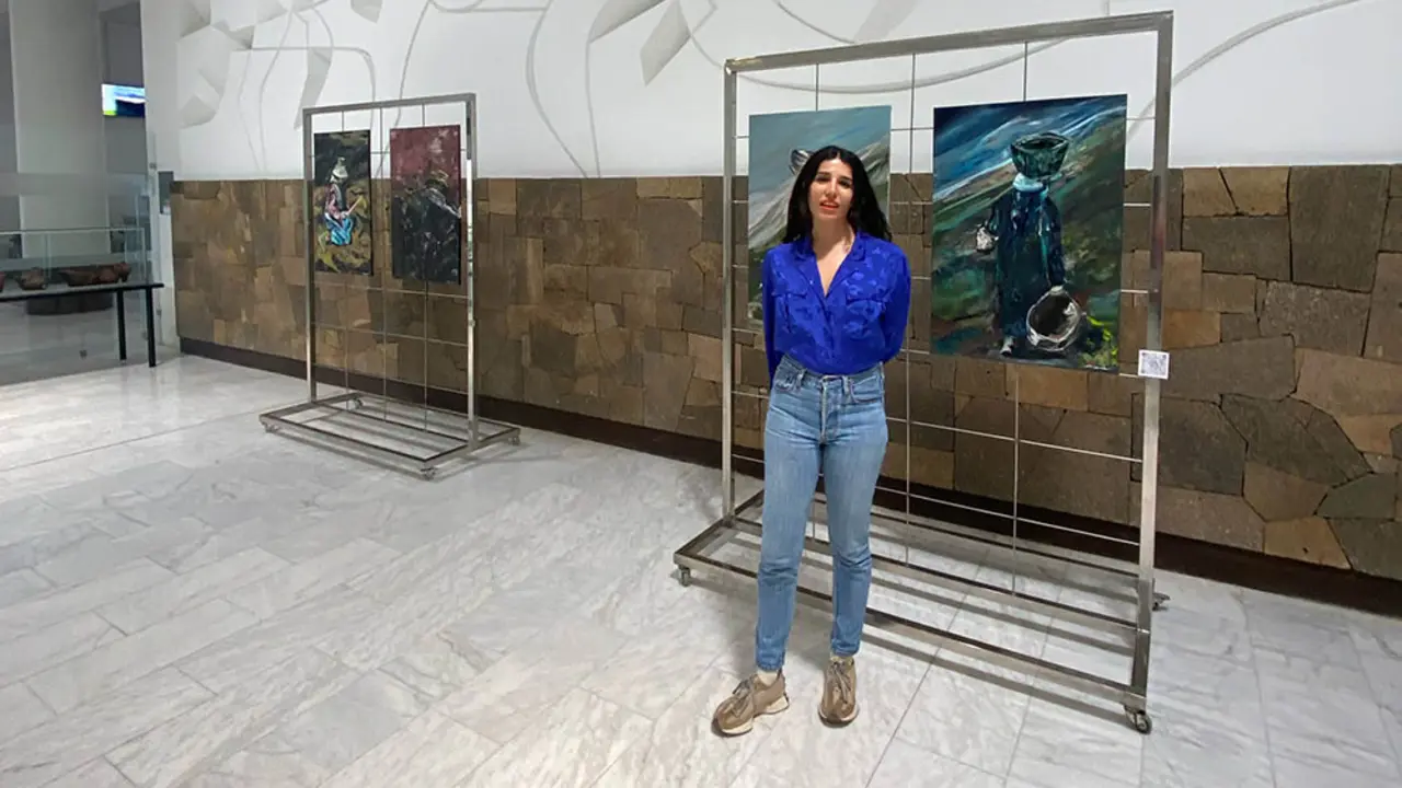 La autora frente a su obra expuesta en la T2