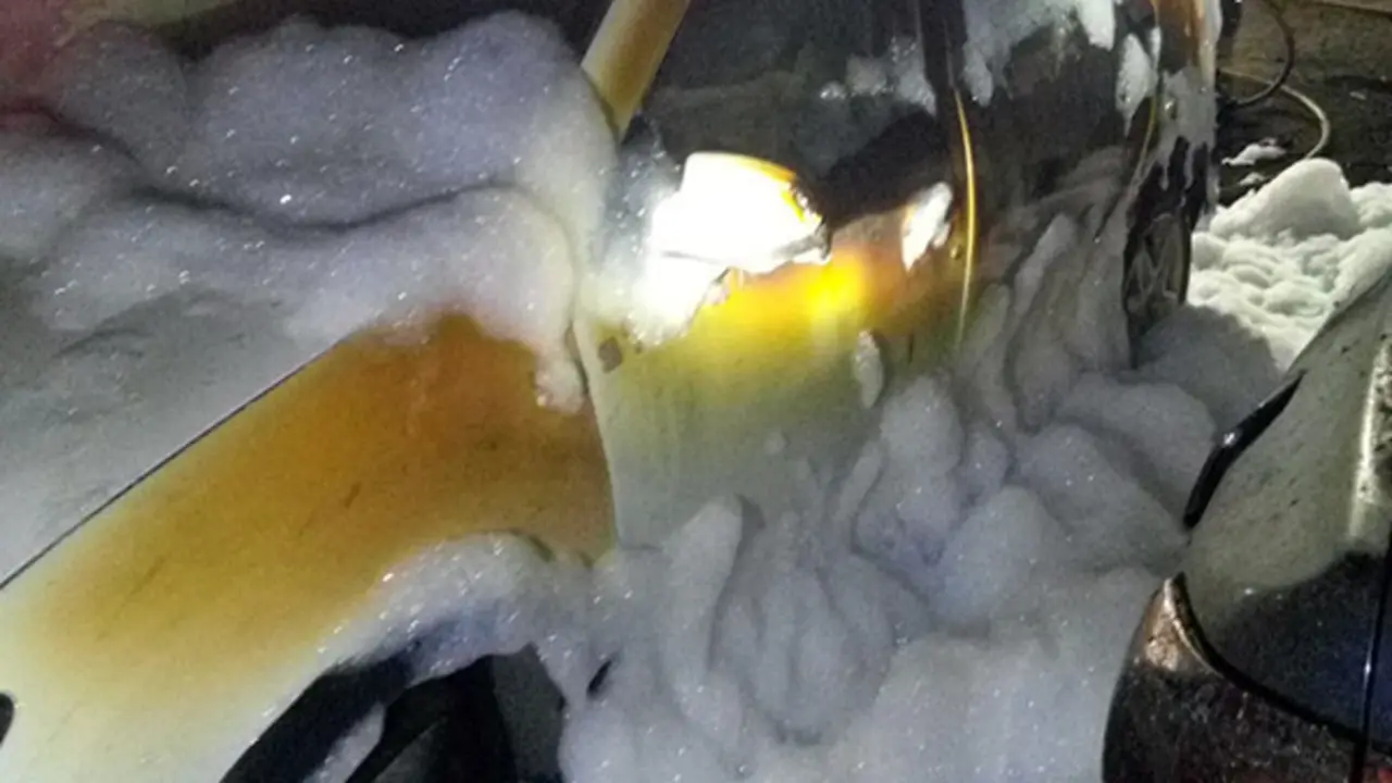 El vehículo afectado por el fuego, totalmente cubierto de espuma