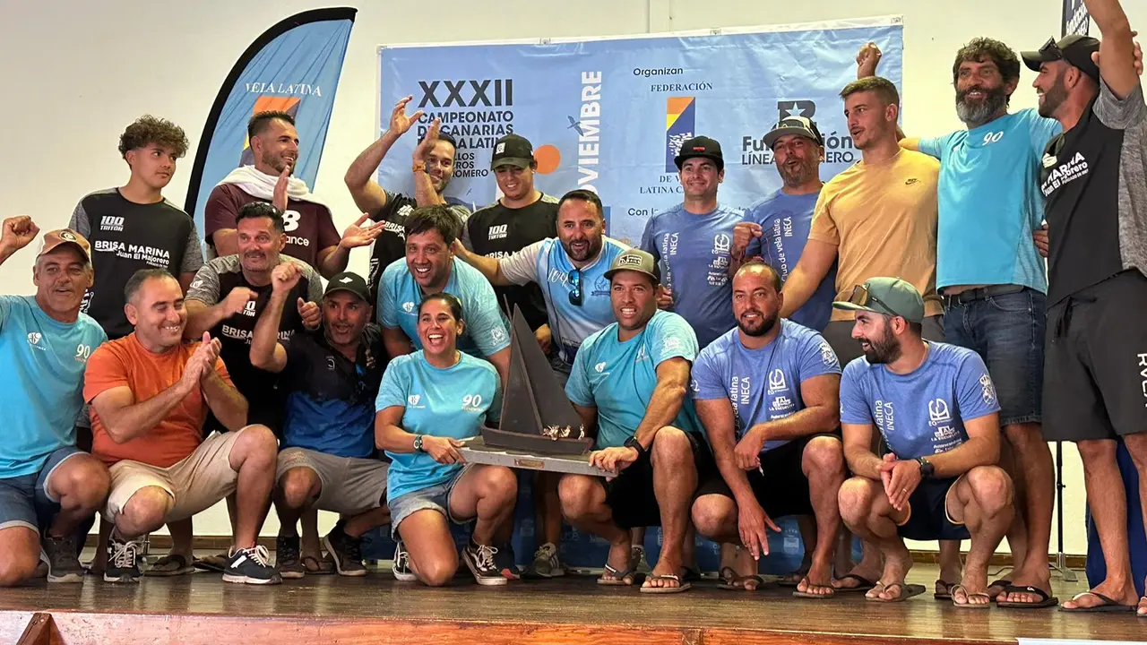 Foto de familia de los equipos del municipio de Yaiza con Virgina Morales, en primer plano, sosteniendo el trofeo de campeones.