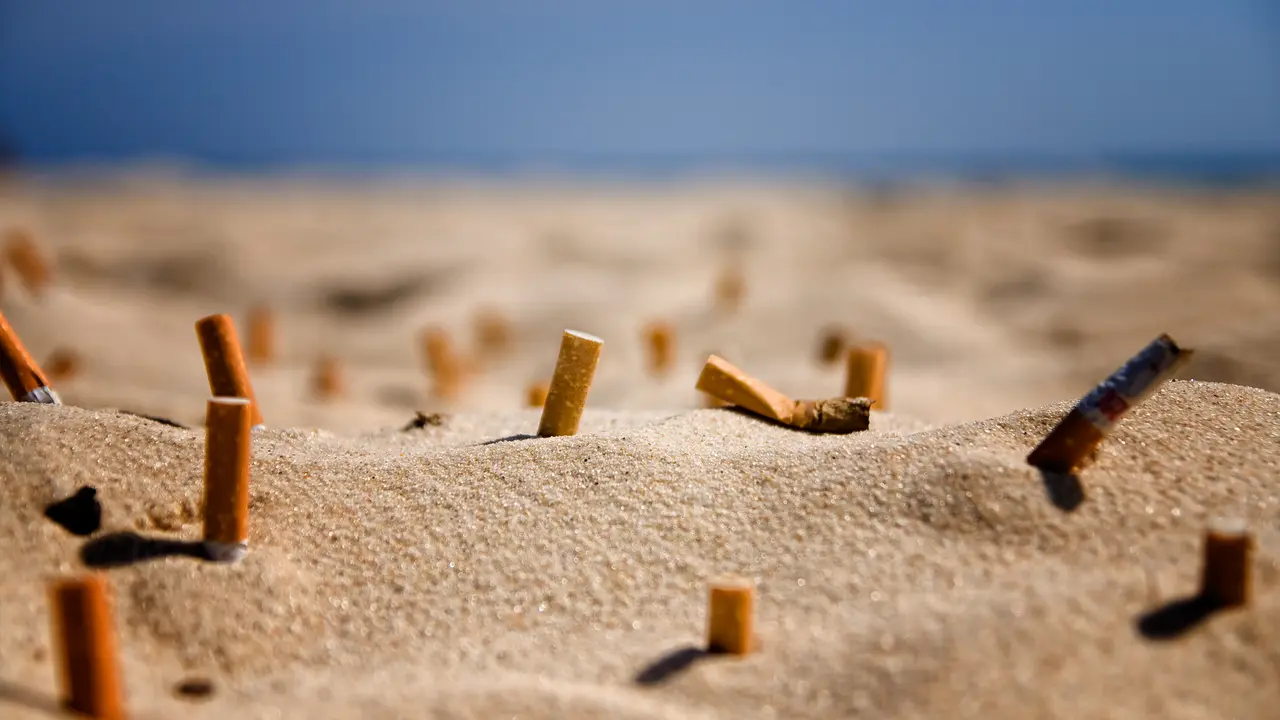 Colillas de cigarrillos en la arena de una playa.