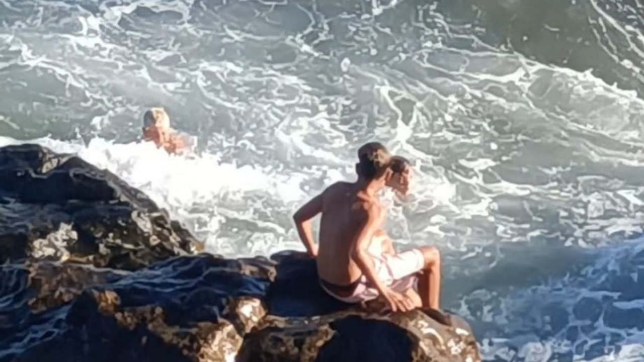 Personas ba&ntilde;&aacute;ndose en una playa de piedras.