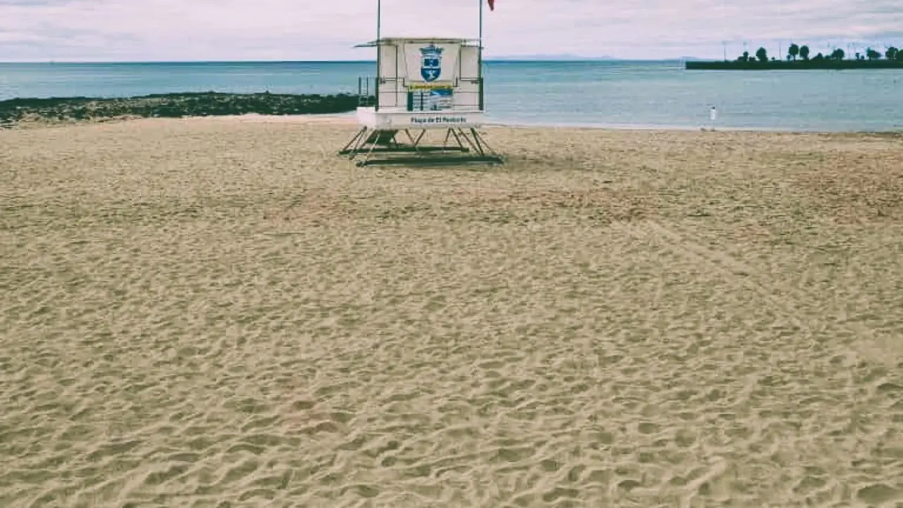 Izada la bandera roja en la Playa de El Reducto, Al fondo a la derecha la Punta del Camello donde el Consorcio del Agua y Canal Gestión tienen en aliviadero del emisario, originario de la contaminación
