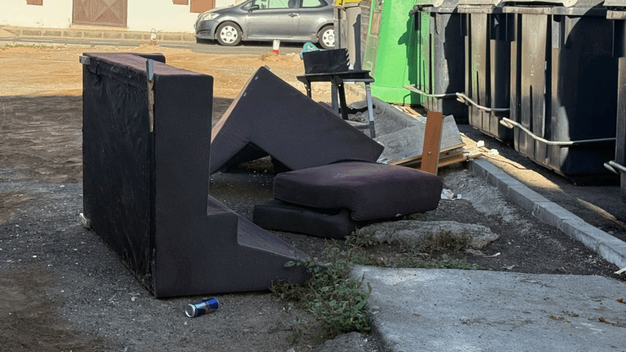 Sillones abandonados junto a contenedores
